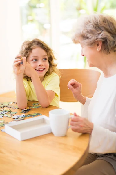 Мальчик и его бабушка собирают головоломку вместе — стоковое фото