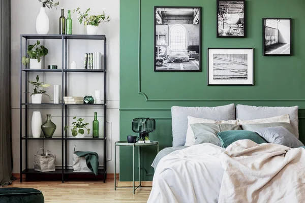 Galeria czarno-białego plakatu na zielonej ścianie za łóżkiem king size z poduszkami i kocem — Zdjęcie stockowe