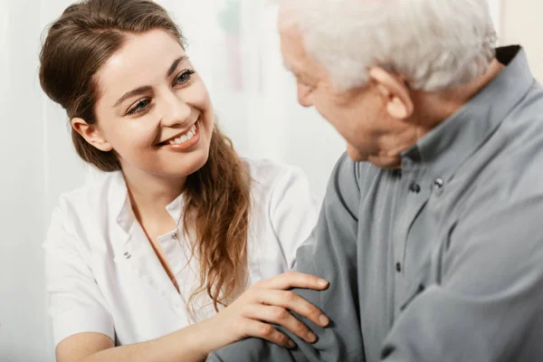 Beautiful volunteer smiling at senior man at nursing home — Stock Photo, Image