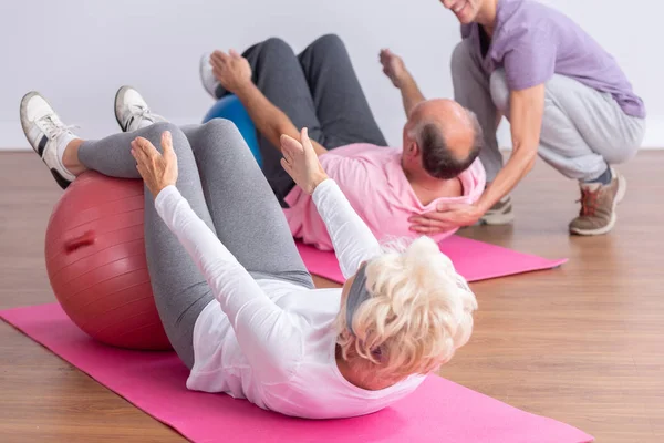 Starszy mężczyzna i kobieta robi pompki w centrum fitness — Zdjęcie stockowe