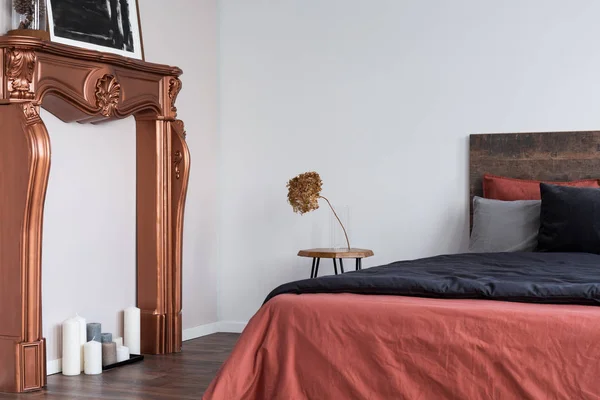 Modern kopparfärgad öppen spis Portal står bredvid trä sängen — Stockfoto