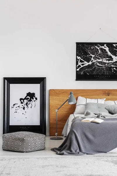 Czarna mapa na białej ścianie nad drewnianą zagarnią w prostym wnętrzu sypialni — Zdjęcie stockowe