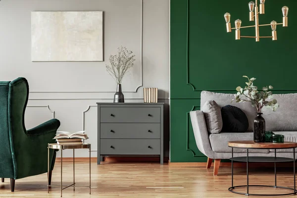Interior de la sala de estar de moda con cómoda de madera, sofá escandinavo y sillón verde esmeralda —  Fotos de Stock