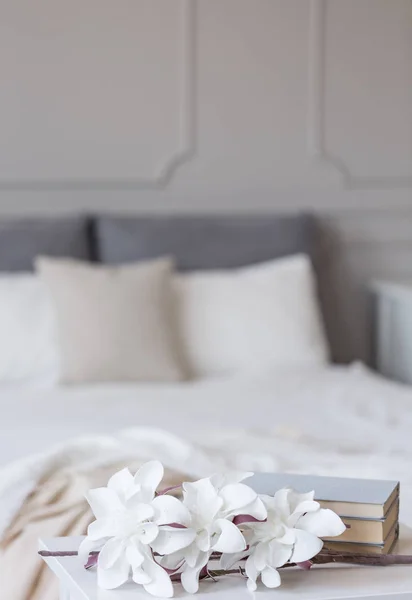 上品なベッドルームのインテリアで快適なベッドの前に花や本 — ストック写真