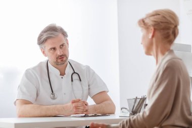 Yakışıklı orta yaş doktor ve kadın hasta hastane ofisinde