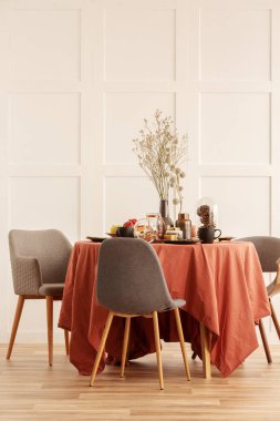 Koyu turuncu masa örtüsü ile kaplı yemek masasında vazo kuru çiçekler