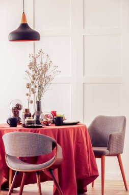 Koyu turuncu masa örtüsü ile kaplı yemek masasında vazo kuru çiçekler