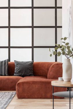 Şık oturma odasında ahşap sehpa üzerinde beyaz vazo yeşil çiçekler