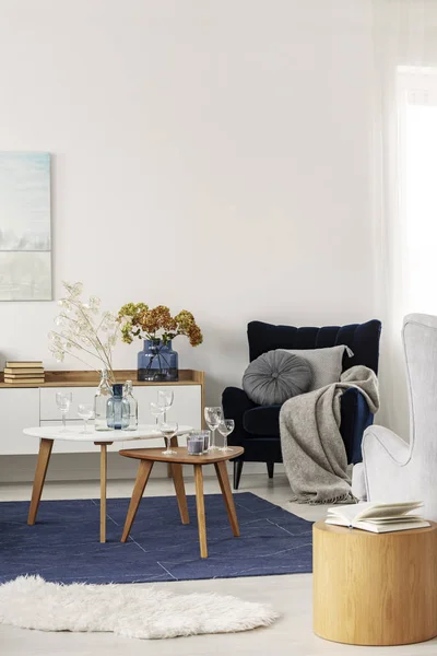 Grey and navy blue living room interior with coffee tables and velvet armchair