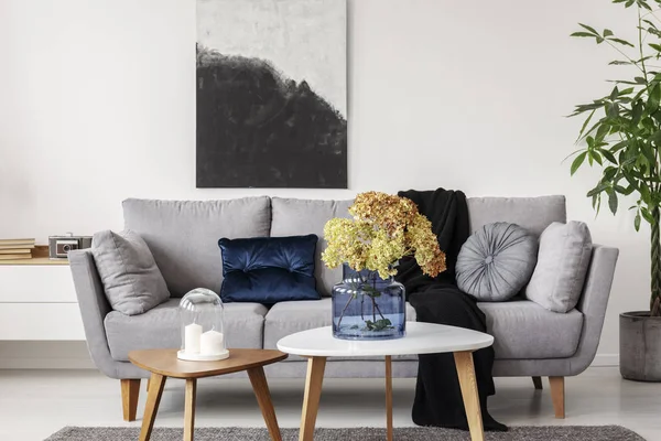 Virágok, kék üveg váza, fából készült dohányzóasztal, elegáns nappali belső — Stock Fotó