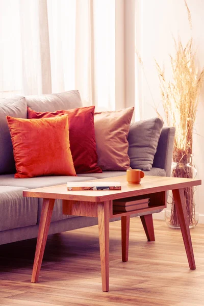 Narancs, piros és bézs párnák szürke kényelmes kanapén elegáns nappaliban belső — Stock Fotó