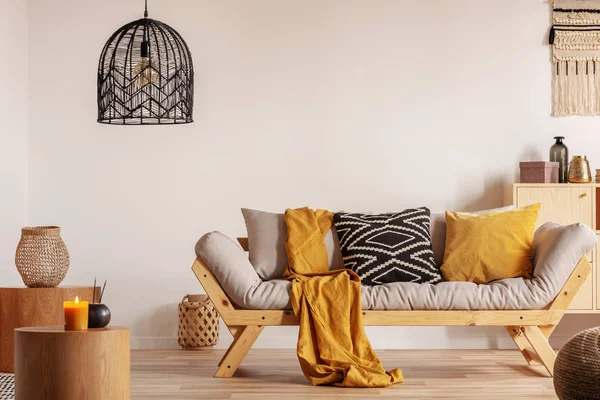 Sofa Skandinavia dengan bantal dan selimut kuning gelap di interior ruang tamu yang cerah dengan lampu gantung hitam — Stok Foto