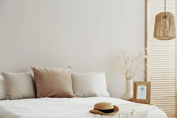 Interior natural del dormitorio de moda con sombrero de mimbre en ropa de cama blanca —  Fotos de Stock