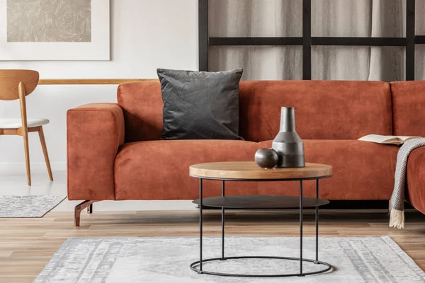 Zwarte vaas op houten salontafel in chique woonkamer interieur met comfortabele sofa — Stockfoto