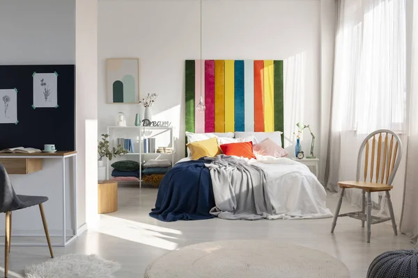 Модний інтер'єр спальні з барвистим узголів'ям, ліжком королівського розміру, стільцем і робочим простором — стокове фото
