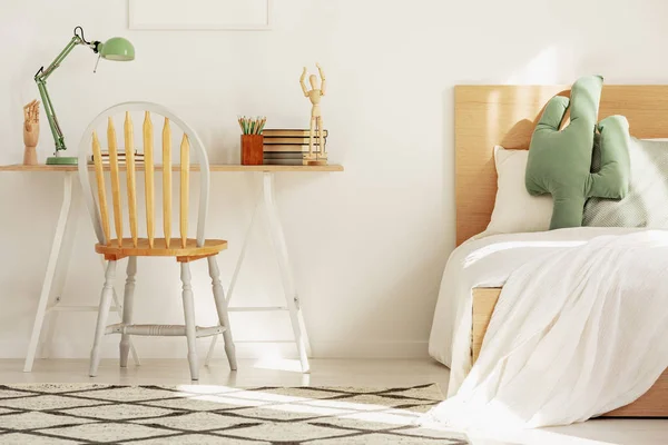 Wooden chair in front of scandinavian desk in elegant bedroom with home office