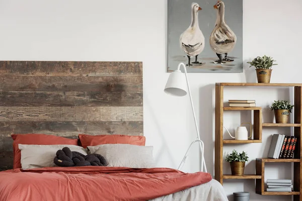 Comfortable king size bed with wooden rustic headboard and white industrial lamp next to it — Stock Photo, Image