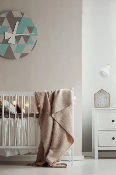 Elegante clack en la pared del elegante interior del dormitorio de bebé con cuna de madera blanca con manta rosa pastel y luces de bolas de algodón —  Fotos de Stock