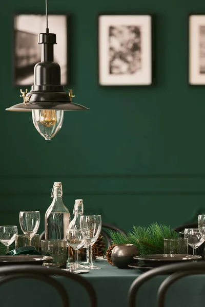 Close-up of a metal lamp hanging above an elegant table with green cloth. Blurred wall with photos in the background. Real photo — Stock Photo, Image