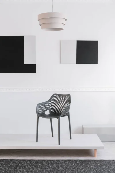 Μοντέρνα γκρίζα Μεταλλική καρέκλα σε λευκή πλατφόρμα σε φανταχτερό εκθεσιακό χώρο — Φωτογραφία Αρχείου
