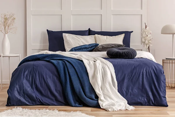 Travesseiro redondo de veludo na cama king size com lençóis azuis e brancos — Fotografia de Stock