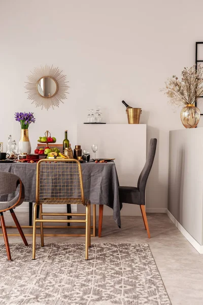 Elegante sedia accanto al tavolo da pranzo con cibo, frutta e fiori — Foto Stock