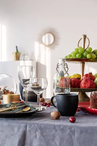 Taza negra, copas de vino y frutas en la mesa del comedor — Foto de Stock
