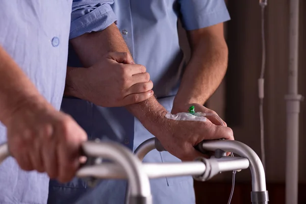 Close-up de mãos de homem sênior segurando walker, apoiando enfermeira masculina em seu site — Fotografia de Stock