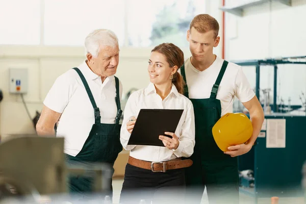 Two stock workers in dark green uniforms and office manager checking delivery — Stock Photo, Image