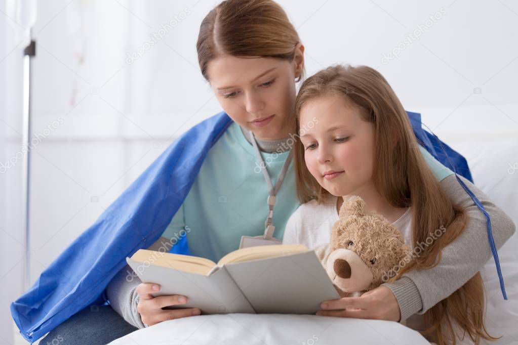 Young blond girl and a volunteer reading her