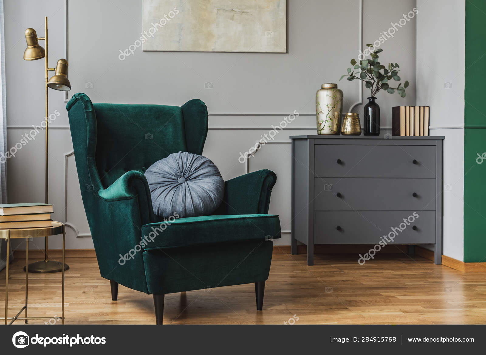 emerald green armchair with pillow next to grey wooden commode in dark  living room interior 284915768