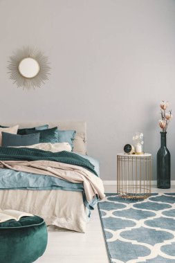 Bej ve zümrüt yeşili yatak ile güzel yatak odası iç saat ile trendy komodinin yanında vazo gibi şık şişe çiçekler