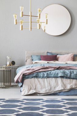 Mavi, bej ve pastel pembe yatak ile kral boy yatak üzerinde ahşap çerçeveli yuvarlak ayna