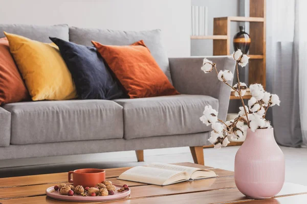 Nahaufnahme eines eleganten Holztisches im trendigen Wohnzimmerinterieur mit grauem Sofa mit Kissen — Stockfoto