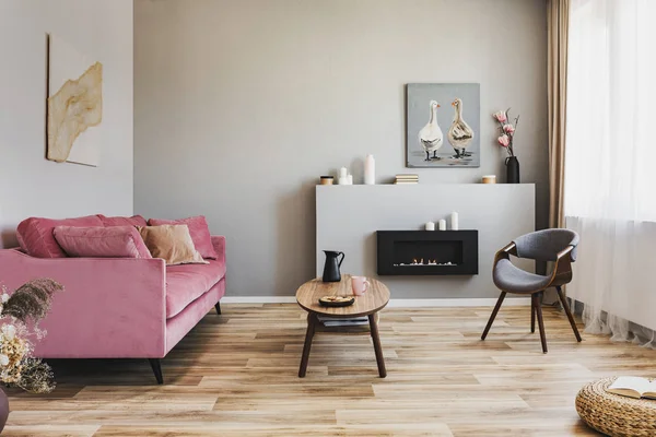 Elegante soggiorno interno con divano rosa pastello, tavolino in legno ed eco camino — Foto Stock