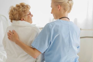 Bakım doktor bir hastane yatağında üst düzey bir hasta yanında oturan ve onu geri vuruş