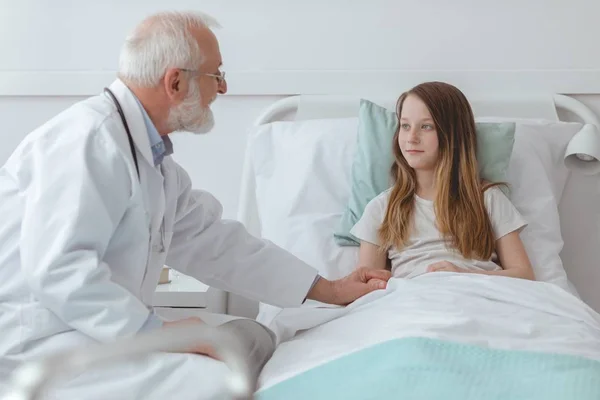 Arzt tröstet ein junges Mädchen im Krankenhaus — Stockfoto
