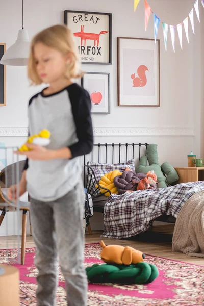 Niewyraźne blond dziecko stoi w kolorowej sypialni pełnej konstrukcji f — Zdjęcie stockowe