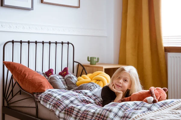 Lachende jongen leggen in haar bed op de geruite Flanel bedclothe — Stockfoto