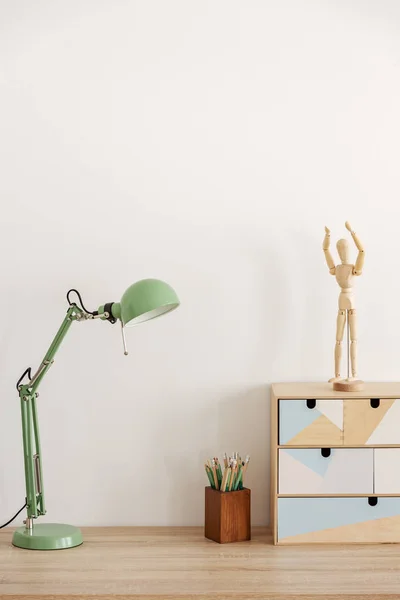 Пастельная мятная лампа на деревянном столе с книгами, пространство для копирования на пустой белой стене — стоковое фото