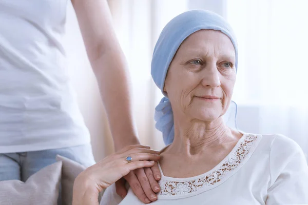 Femme âgée portant un foulard bleu, souffrant d'un cancer du poumon, main de fille sur son bras comme signe de soutien — Photo