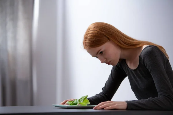 Fille regardant une laitue sur une assiette devant elle — Photo