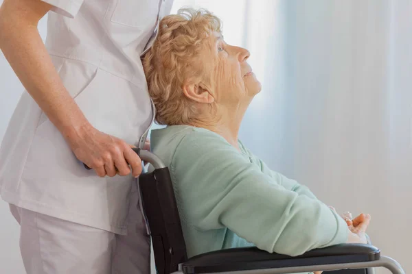 Femme âgée positive en fauteuil roulant avec son médecin serviable à l'établissement de soins infirmiers — Photo