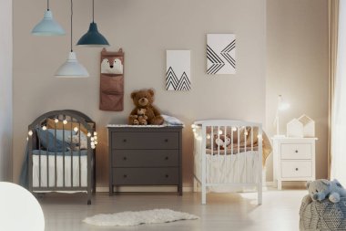 Ahşap beşik, bej duvarlar ve çekmecegri bir göğüs üzerinde sevimli oyuncak ayılar ile kardeşler için bir pastel yatak odası iç Gerçek fotoğraf