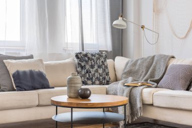 Yastıklar ile İskandinav köşe kanepe önünde yuvarlak ahşap sehpa