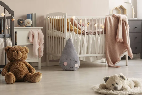 Lindos juguetes de peluche y mantas de color rosa en el acogedor interior del dormitorio para las niñas gemelas con dos cunas y armarios de cabecera. Foto real —  Fotos de Stock