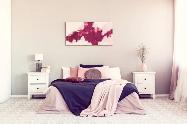 King size bed with pillows and blanket between two wooden nightstand with drawers — Stock Photo, Image