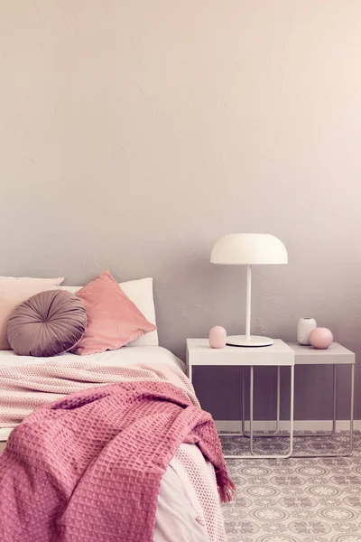 Лампа на білому тумбочці поруч із зручним ліжком королівського розміру з подушками та ковдрою — стокове фото