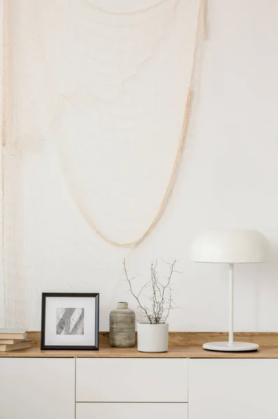 Lâmpada industrial branca, foto no quadro e planta no potenciômetro na tabela de console de madeira na sala de estar elegante com parede branca — Fotografia de Stock