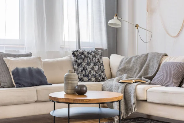 Yastıklar ile İskandinav köşe kanepe önünde yuvarlak ahşap sehpa